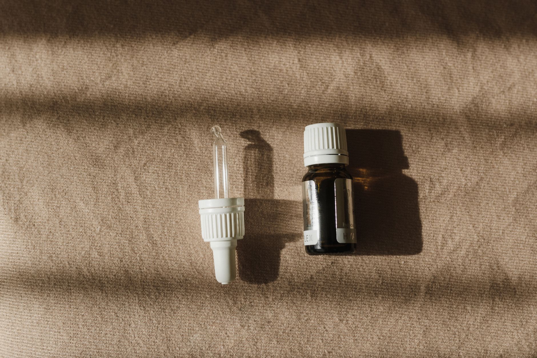 A neutral flat lay of small amber and clear glass bottles on a stone surface.